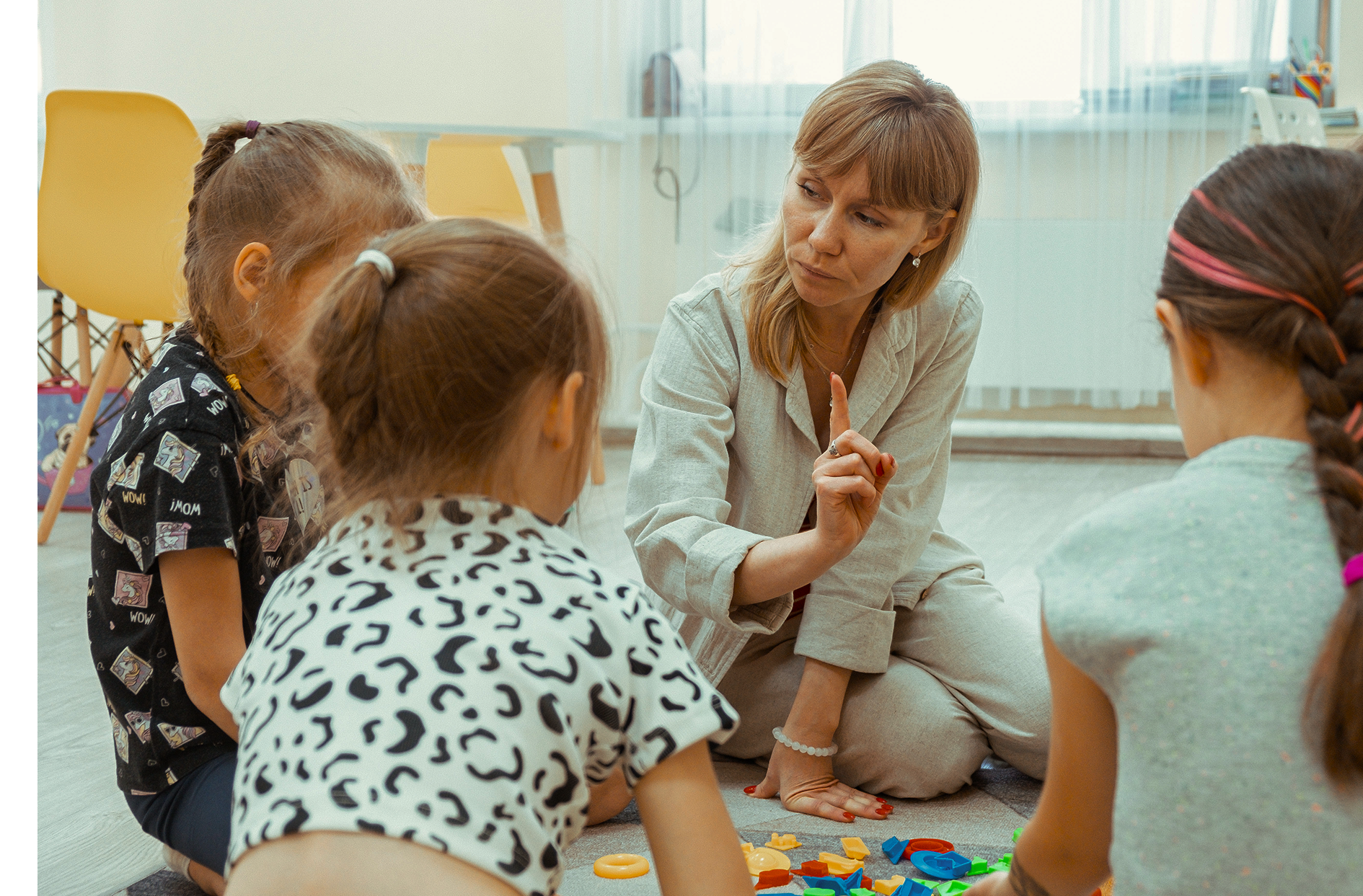 Учитель играет с двумя маленькими детьми.